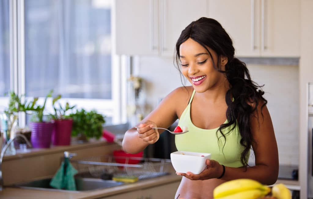 Woman eating healthy food in a kitchen.